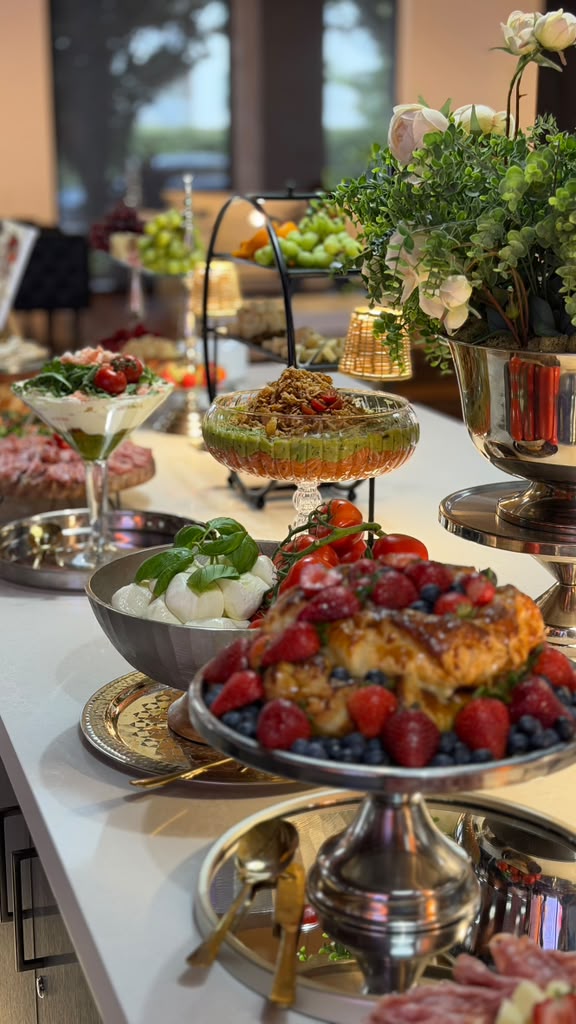 Buffet table with fresh fruit, desserts, cheeses and flowers in elegant decor